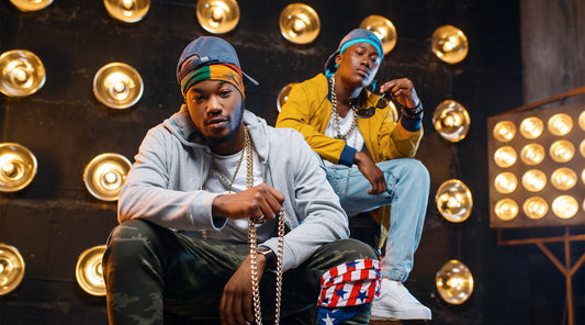 two black rappers sitting on the steps holding gold iced out chains