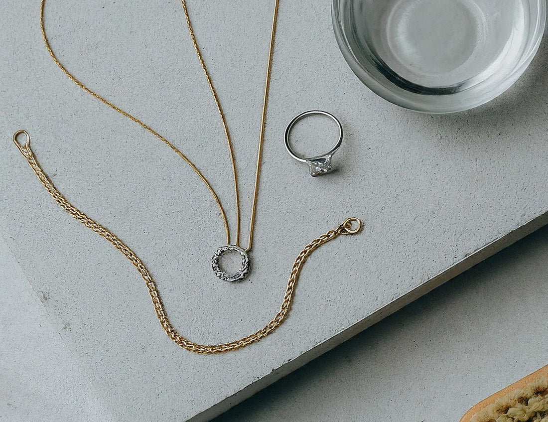  A flat lay photo of jewelry cleaning supplies, including a soft-bristled brush and a bowl of soapy water, on a white background.