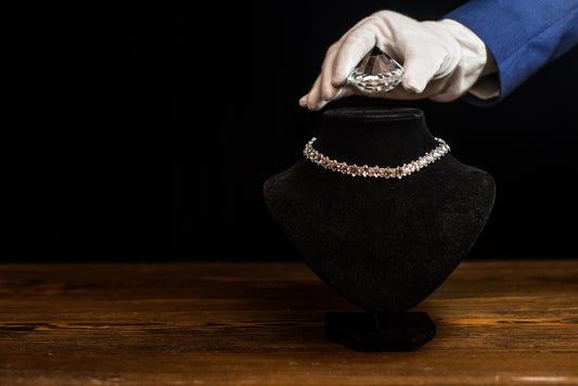 A gloved hand holds a diamond above a necklace, showcasing the luxury and craftsmanship that becomes attainable through Roe Jewelry's financing options.